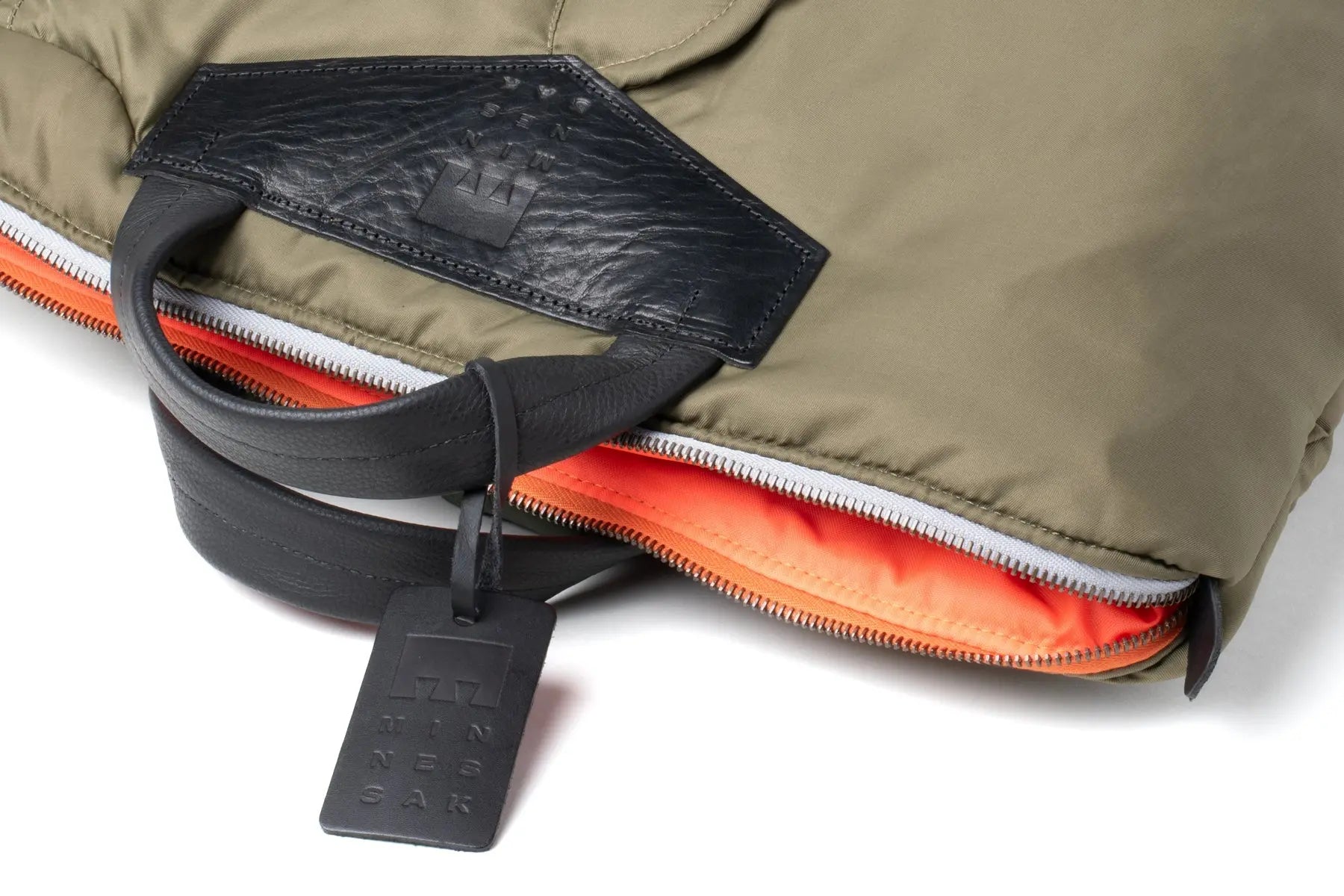 Close-up of a jacket with a zipper and visible brand tag on a white background