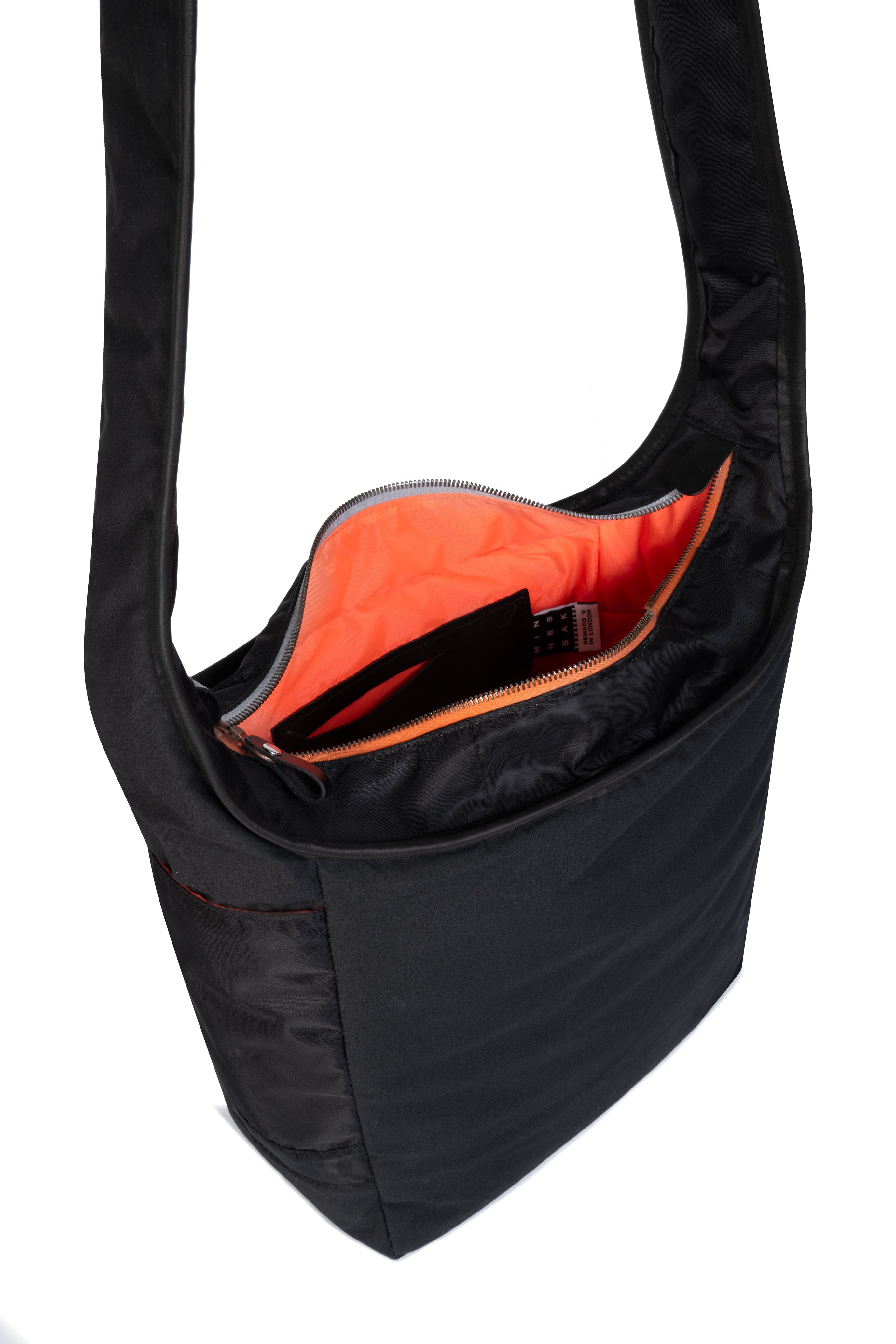 Black shoulder bag with a strap and orange interior on a white background