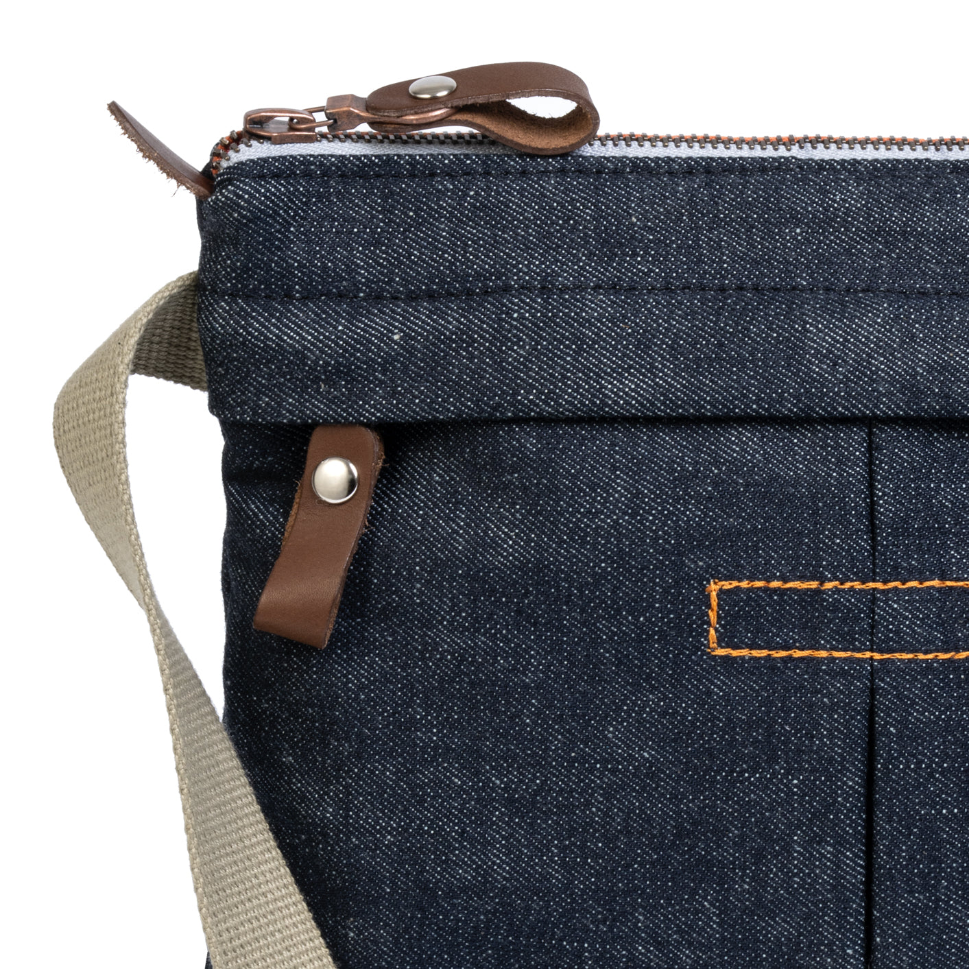 Close-up of a blue denim bag with brown leather straps and stitching on a white background