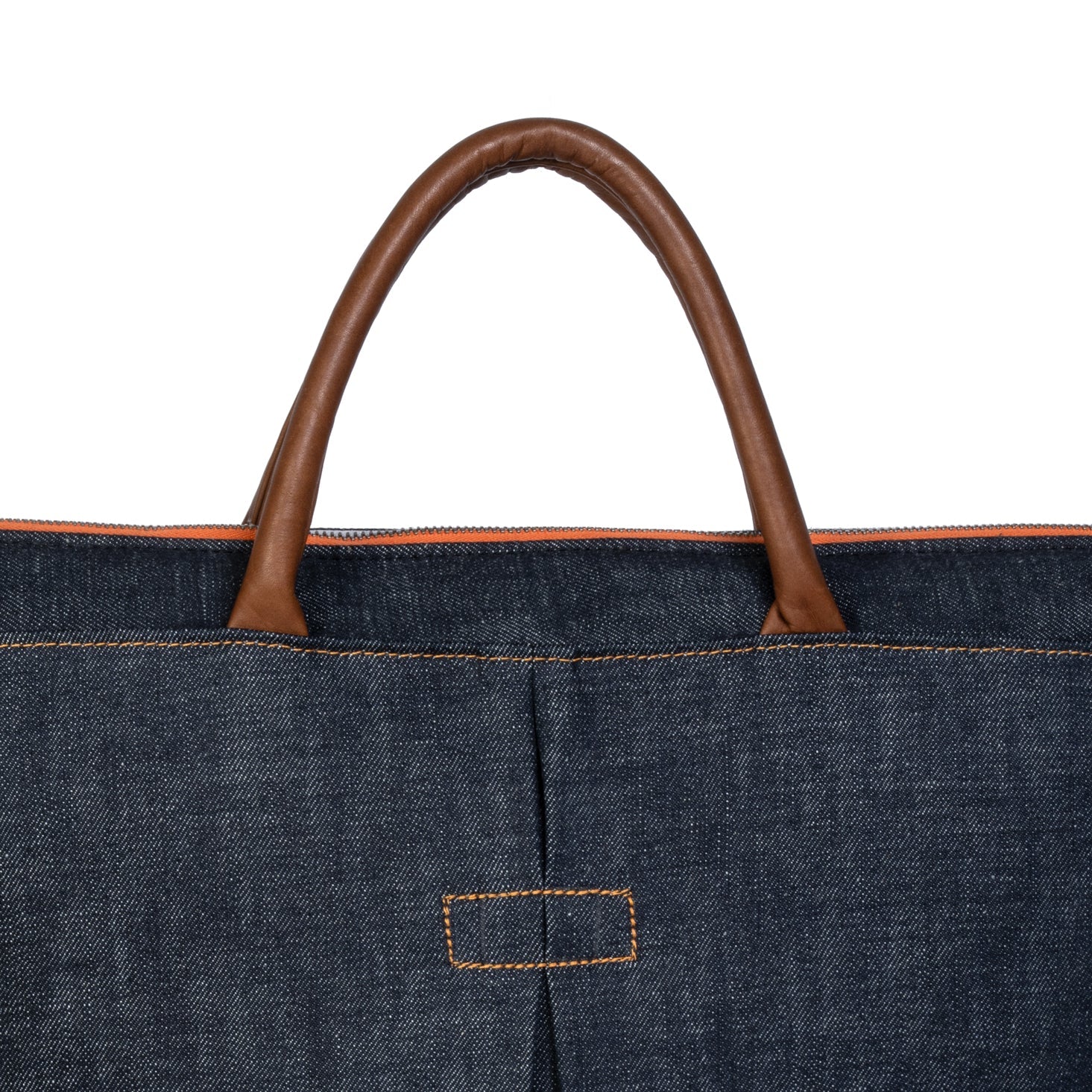 Close-up of a denim bag with brown leather handle on a white background