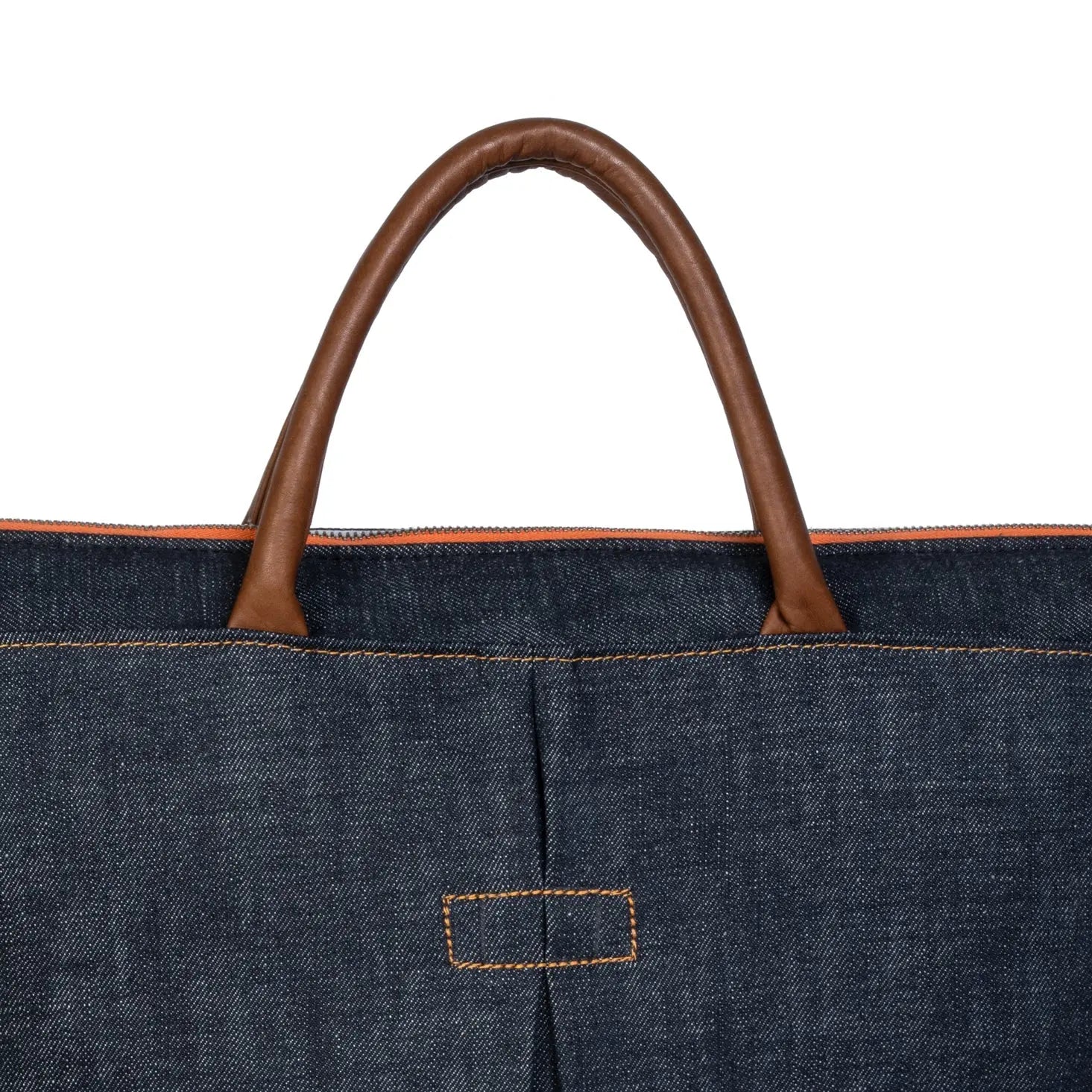 Close-up of a denim bag with brown leather handle on a white background