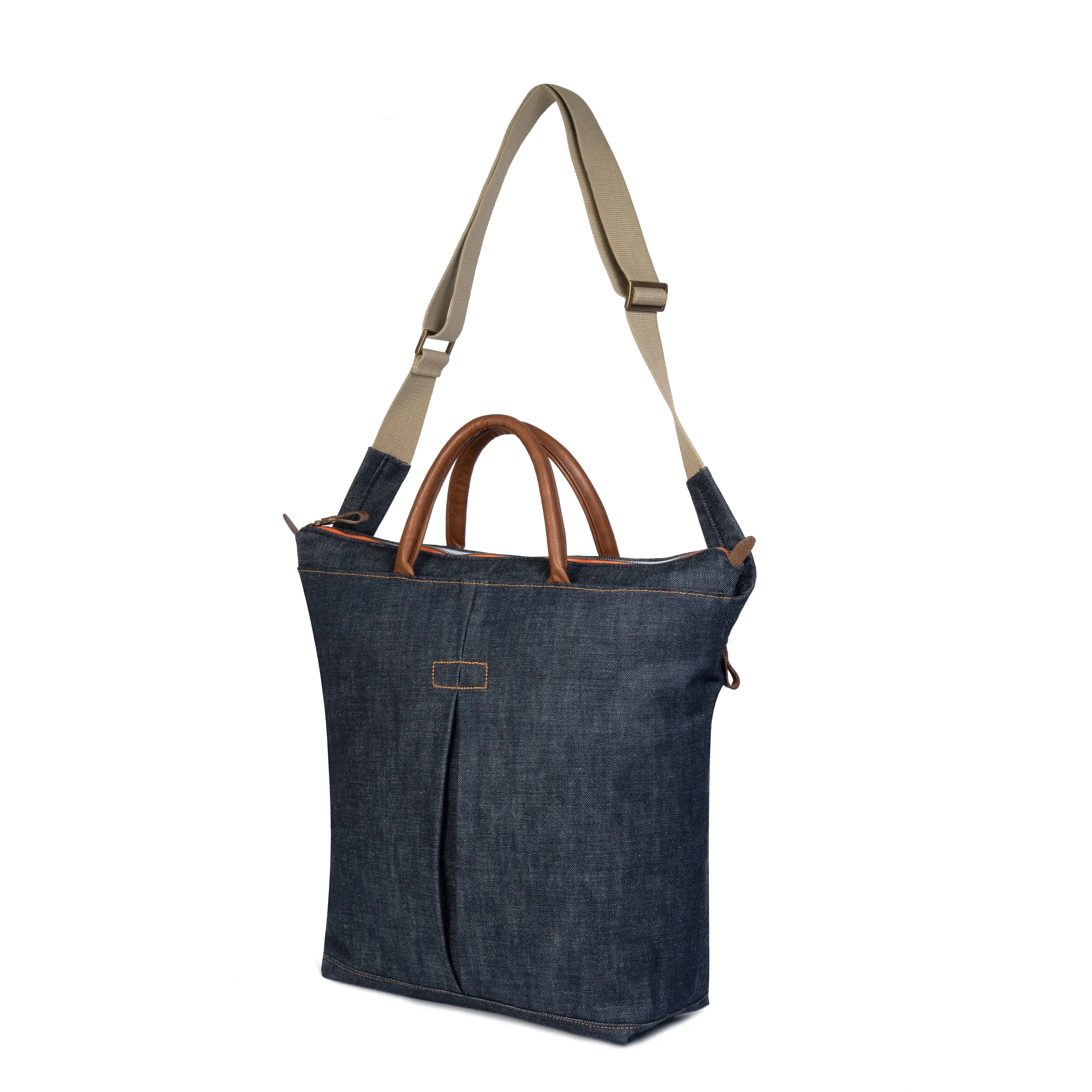 Blue denim tote bag with brown handles and beige strap on a white background