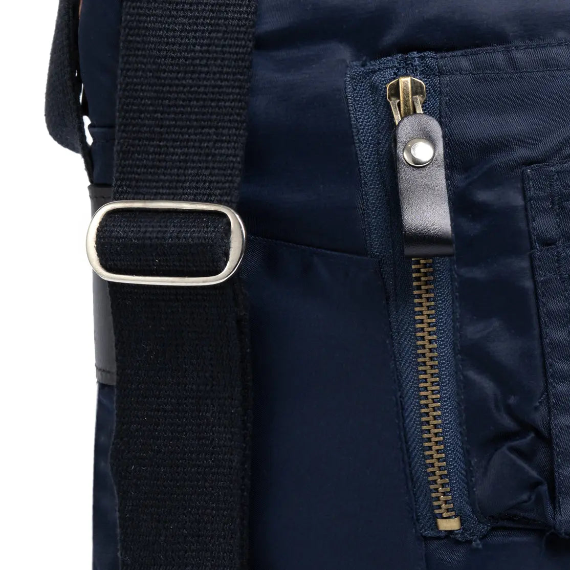 Close-up of a navy blue backpack with a strap and zipper detail on a white background