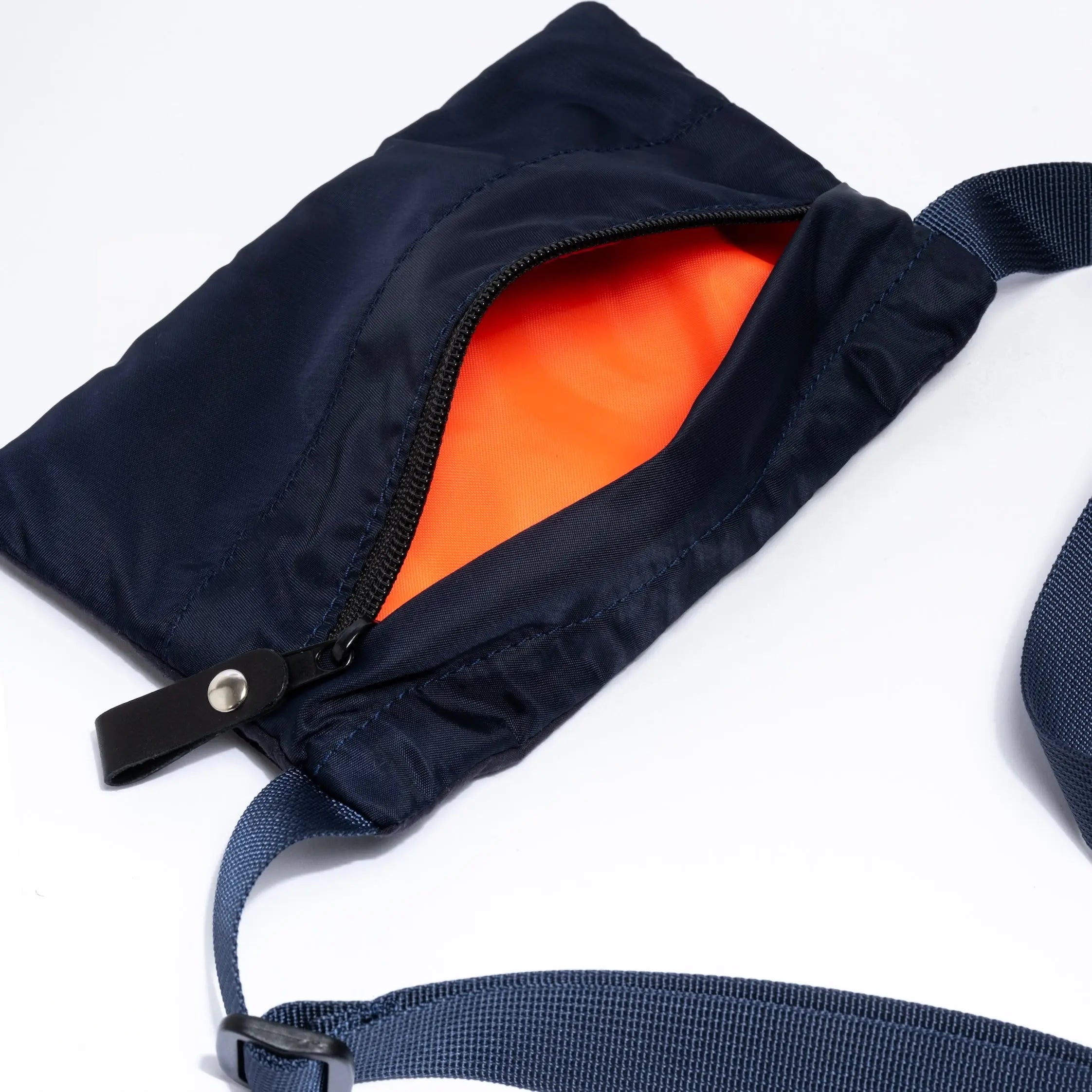 Small cross body bag in navy with strap and internal detail on white background
