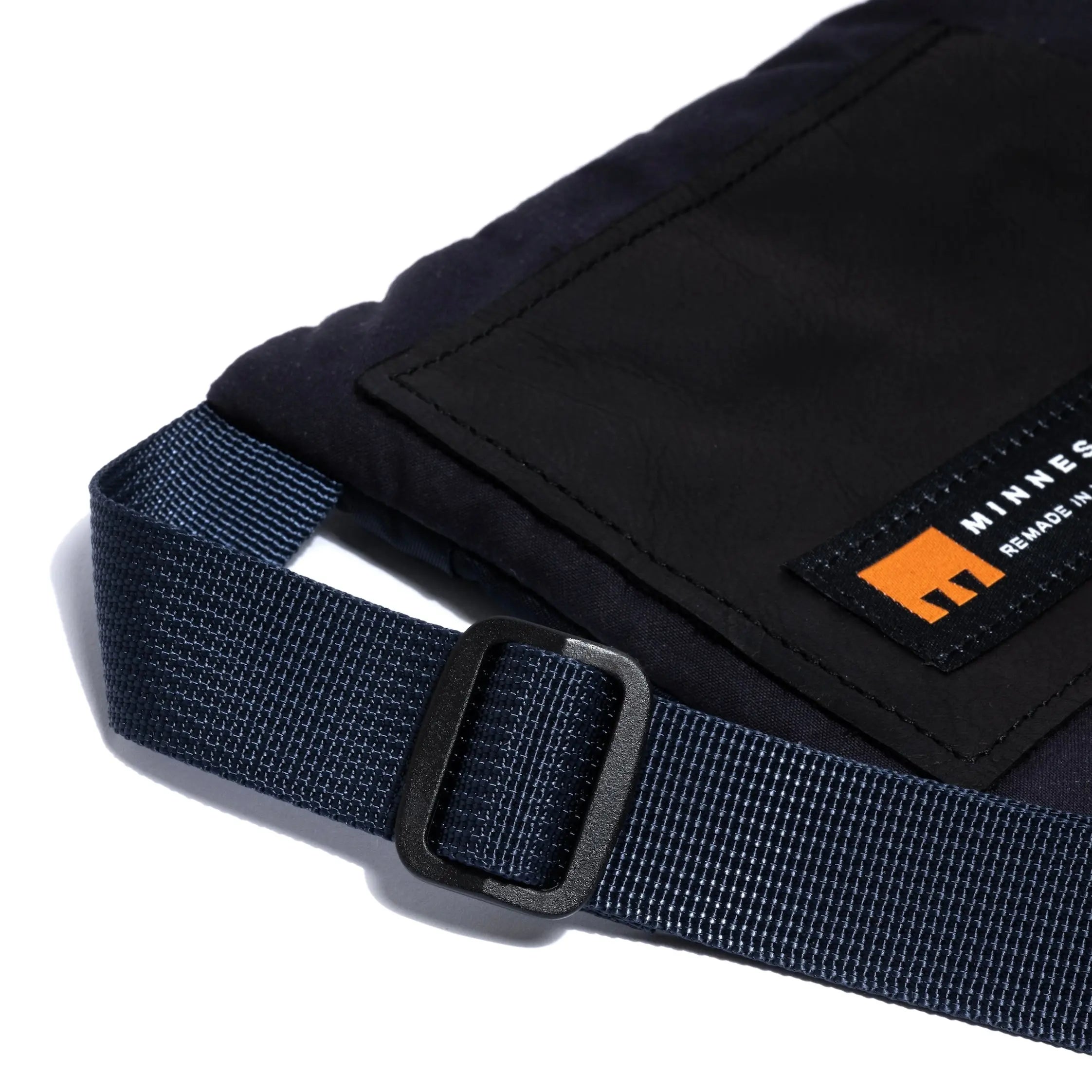 Sall cross body bag in navy showing strap detail and Minnessak logo on a white background