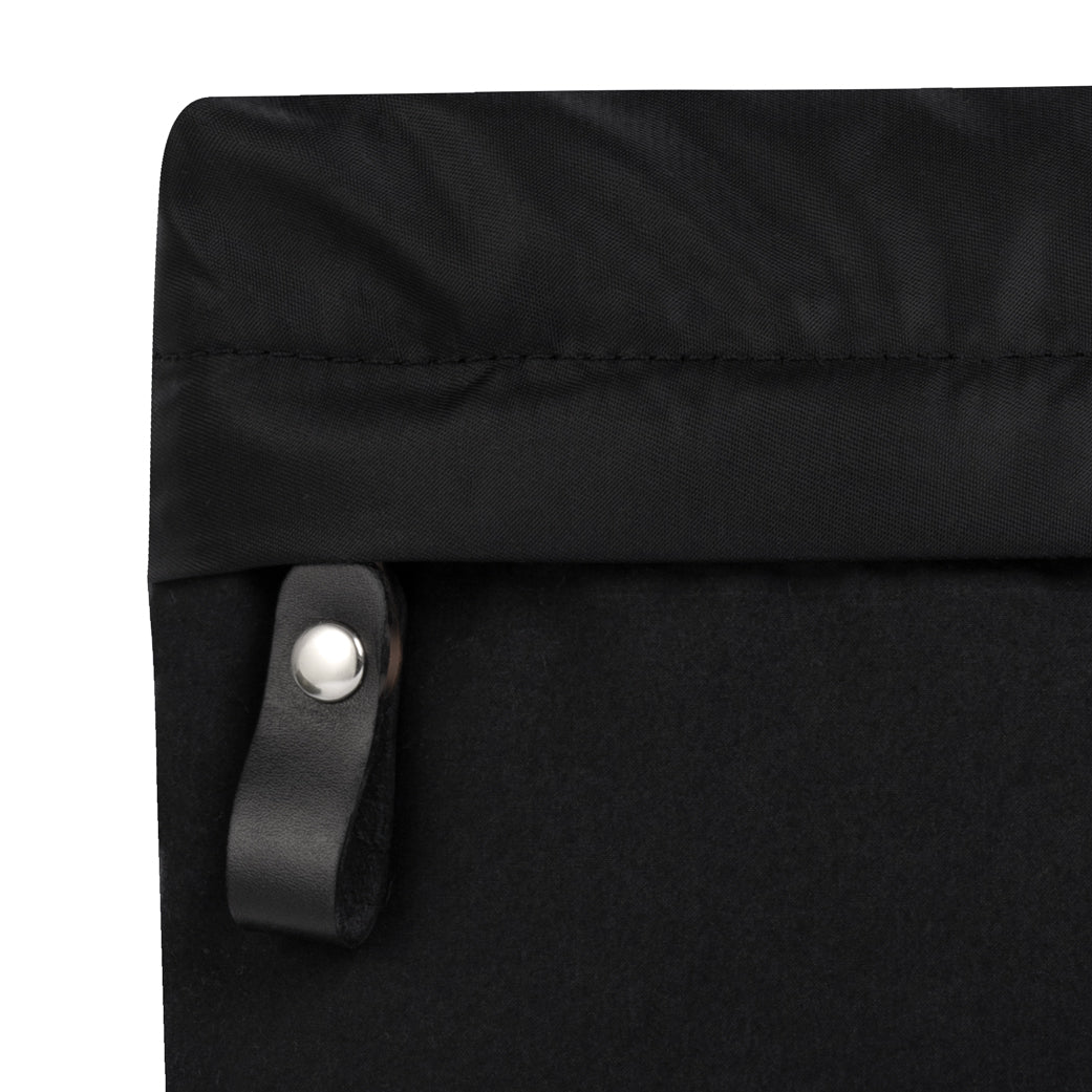 Close-up of a black bag with a leather strap and metal buckle on a white background