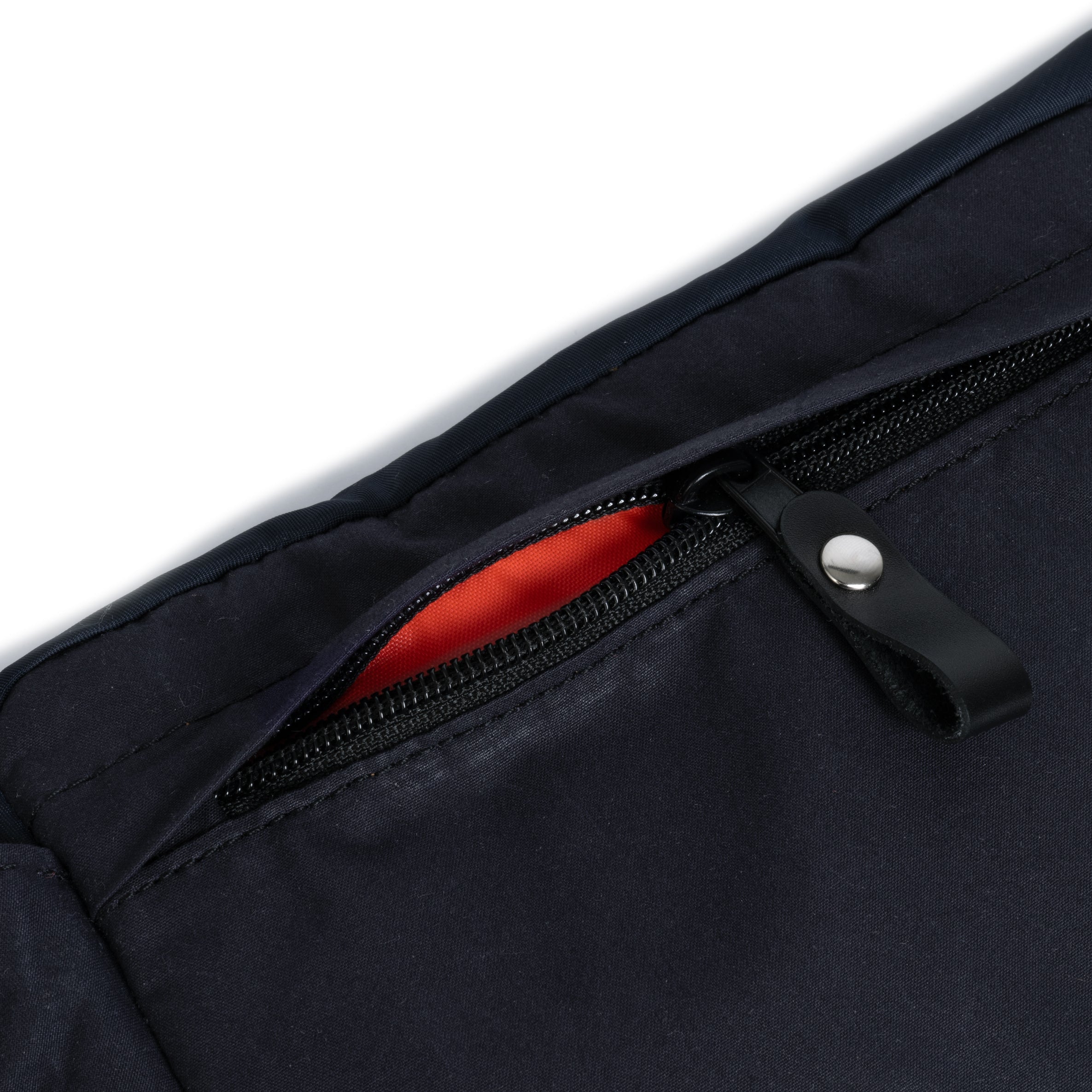 Close-up of a black jacket with a zipper and an orange lining on a white background