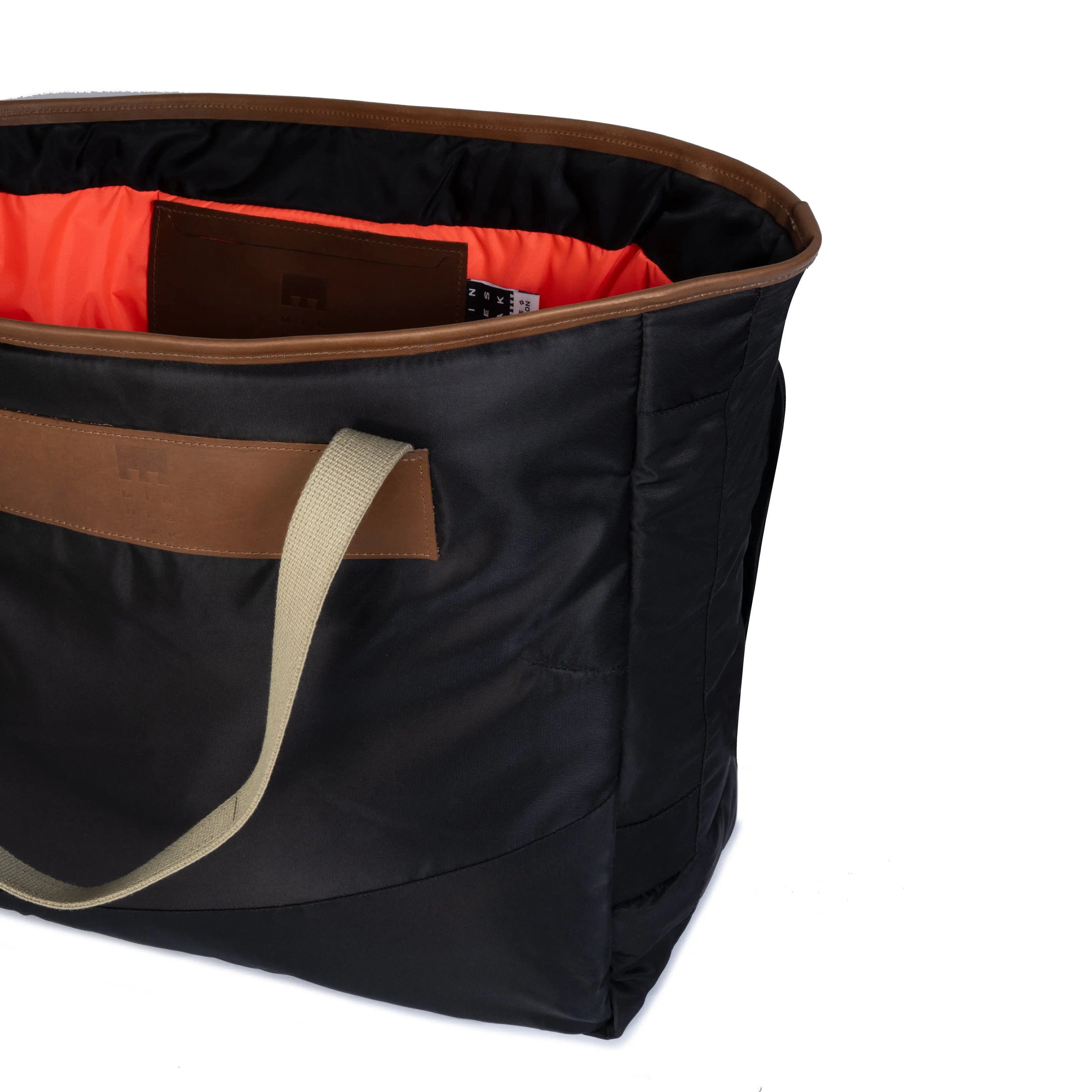 Black bag with brown accents and a beige handle on a white background