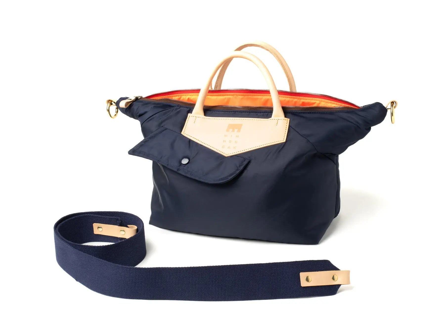 Navy blue handbag with beige handle and strap on a white background