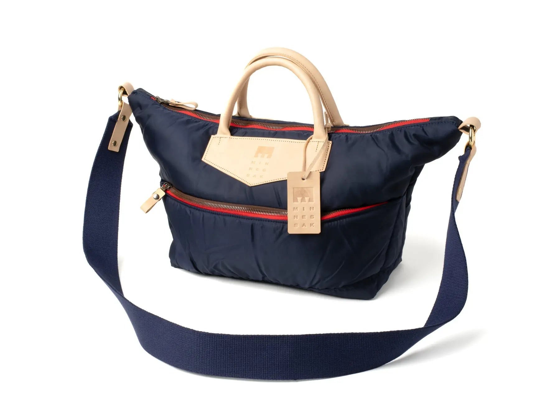 Navy blue handbag with beige handle and strap on a white background