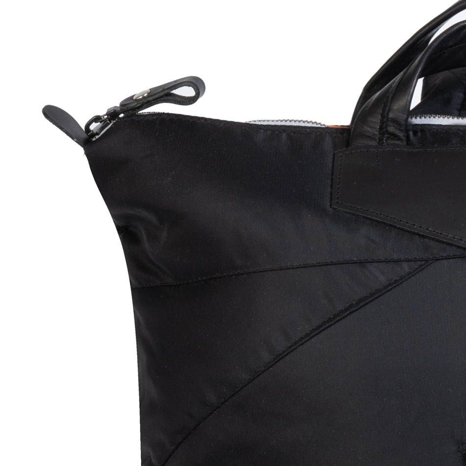 Close-up of a black tote bag with a zipper on a white background