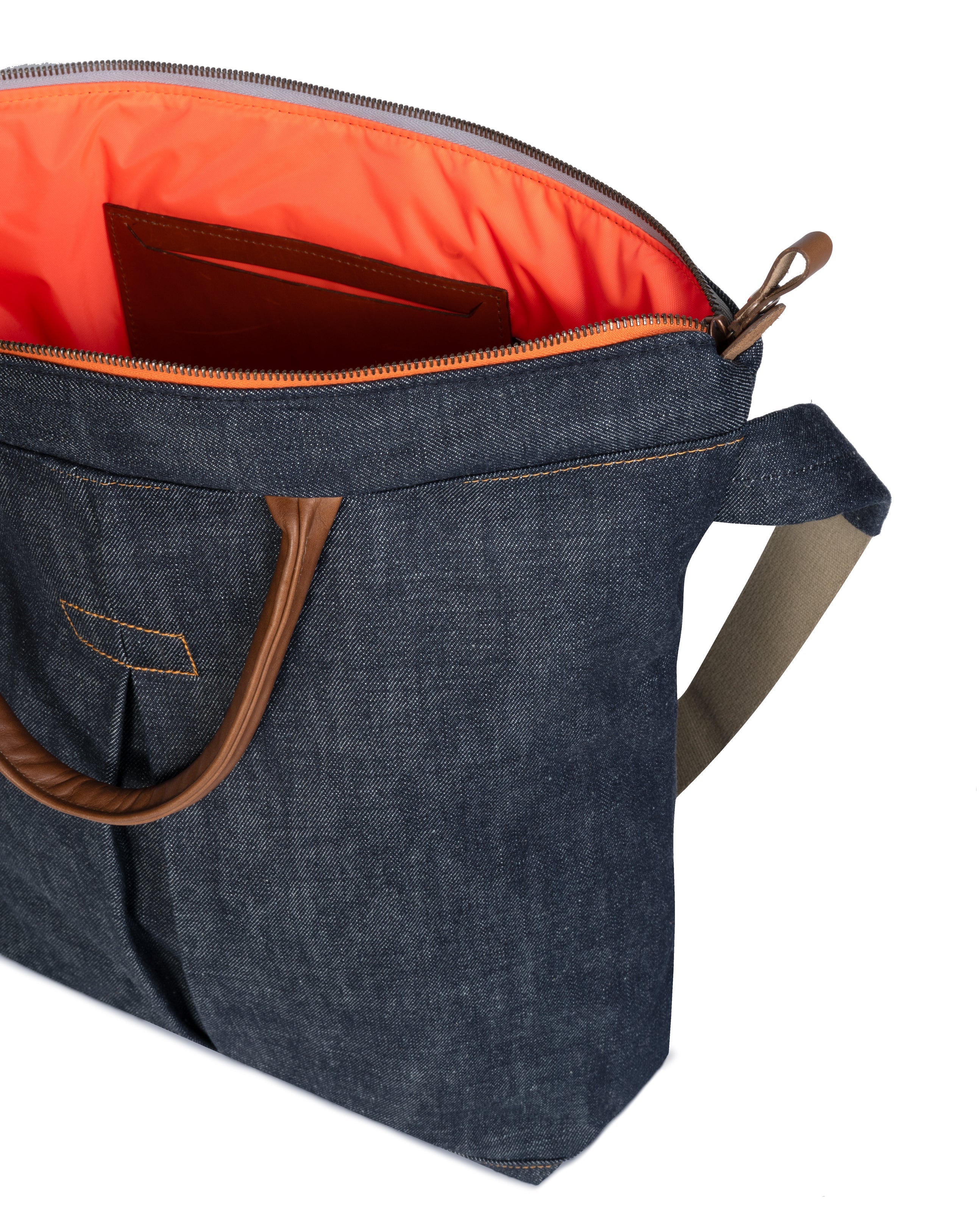 Blue denim bag with brown handles and orange interior on a white background