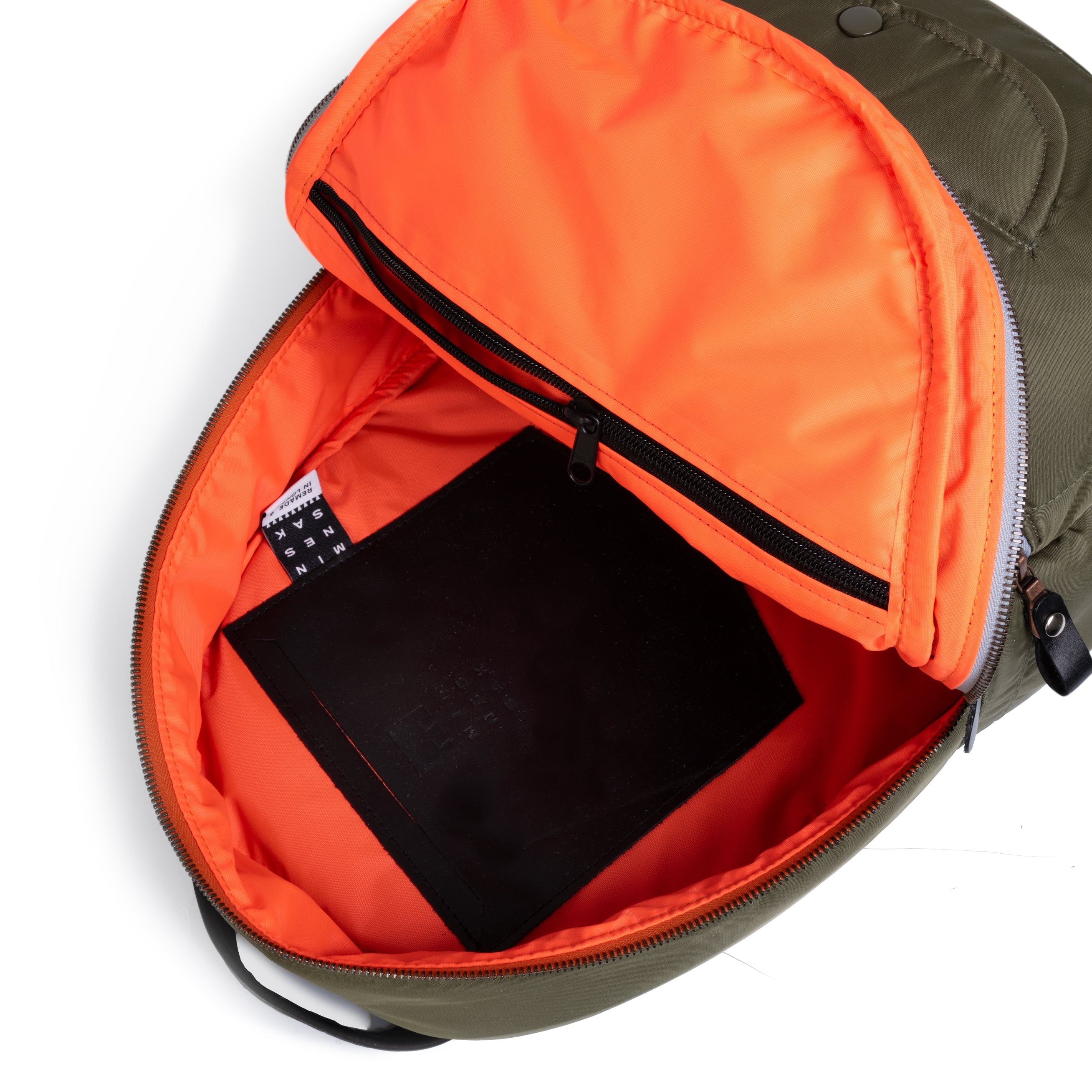Open Olive backpack with orange interior showing a black label on a white background