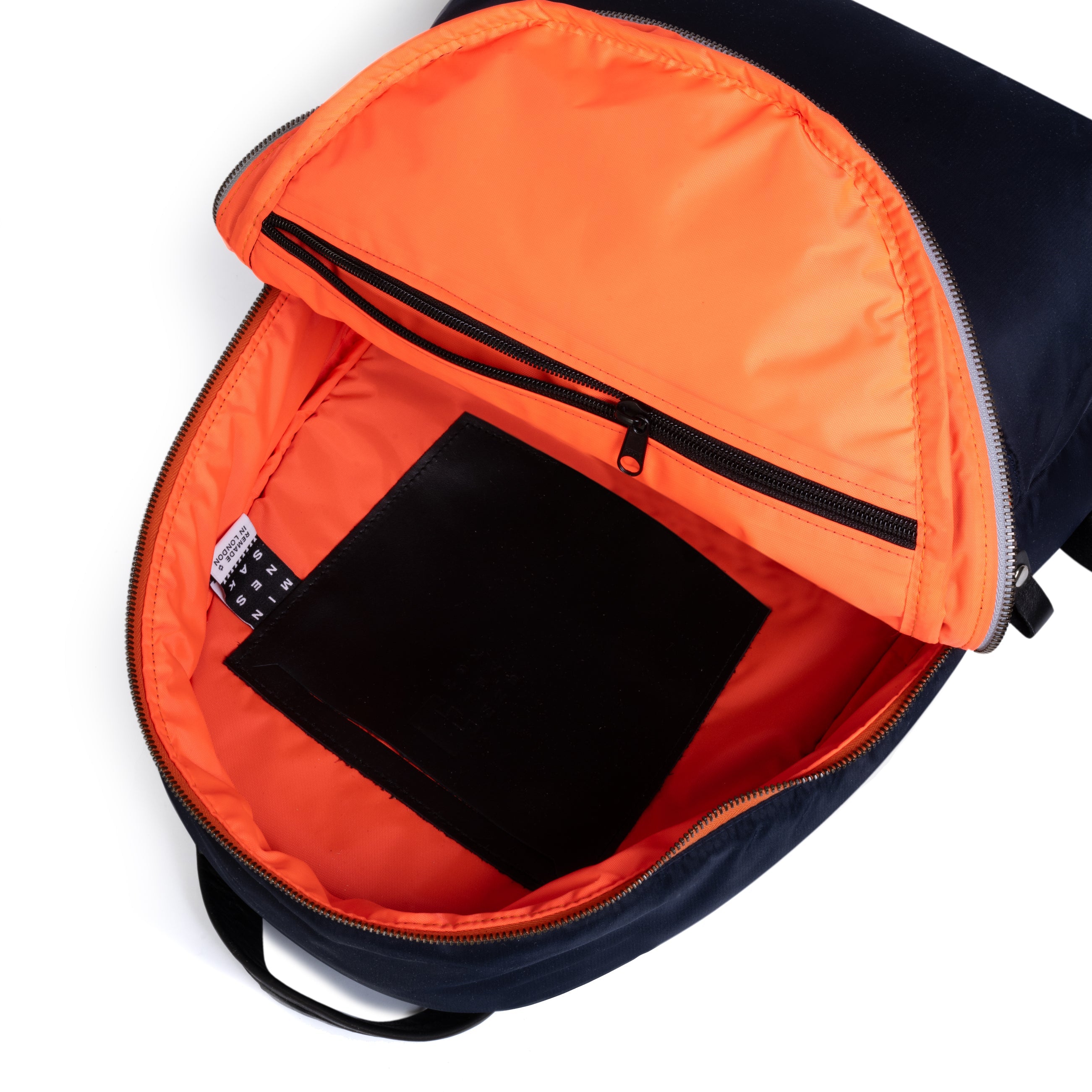 Backpack with orange interior compartment and black tablet inside on a white background