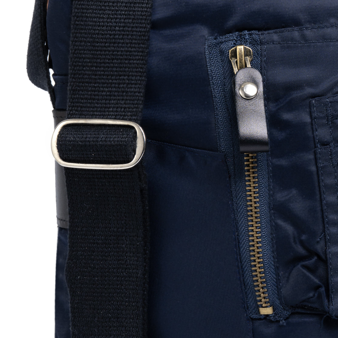 Close-up of a navy blue backpack with a strap and zipper detail on a white background
