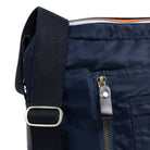 Close-up of a navy blue bag with a black strap and zipper detail.