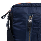 Close-up of a navy blue bag with a zipper and strap on a white background