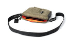 Olive shoulder bag showing orange lining with a black strap on a white background