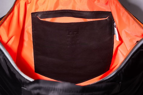 Black Back Up/26 sustainable backpack handmade from repurposed MA-1 flight jacket material with internal, embossed, vintage Italian leather pocket stitched to orange, recycled polyester lining.