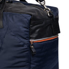 Close-up of a navy blue bag with black leather accents and orange zipper on a white background