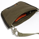 Olive shoulder/cross body bag showing internal orange detail on white background