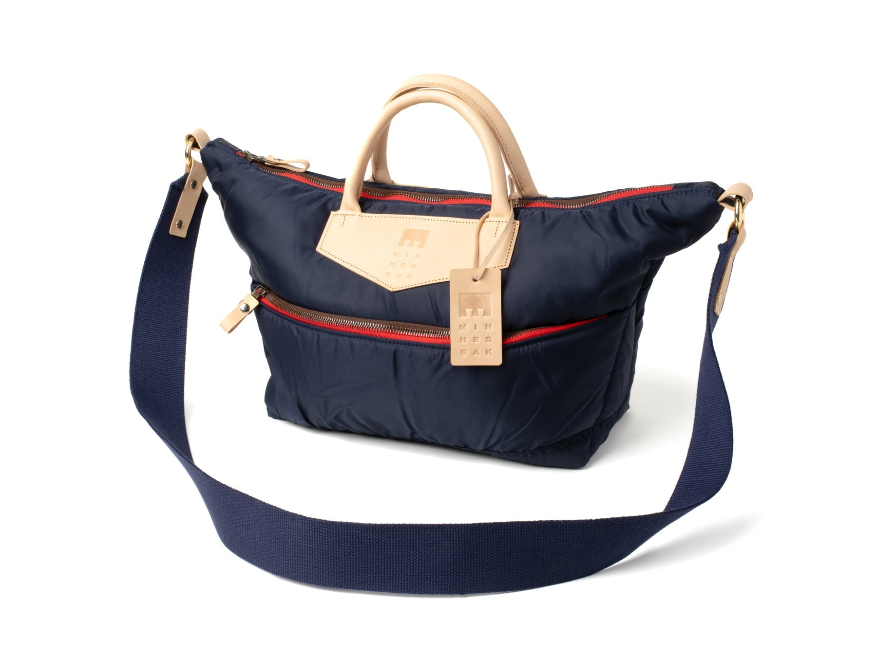 Navy blue handbag with beige handle and strap on a white background
