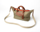 Olive handbag with brown leather accents with strap on a white background
